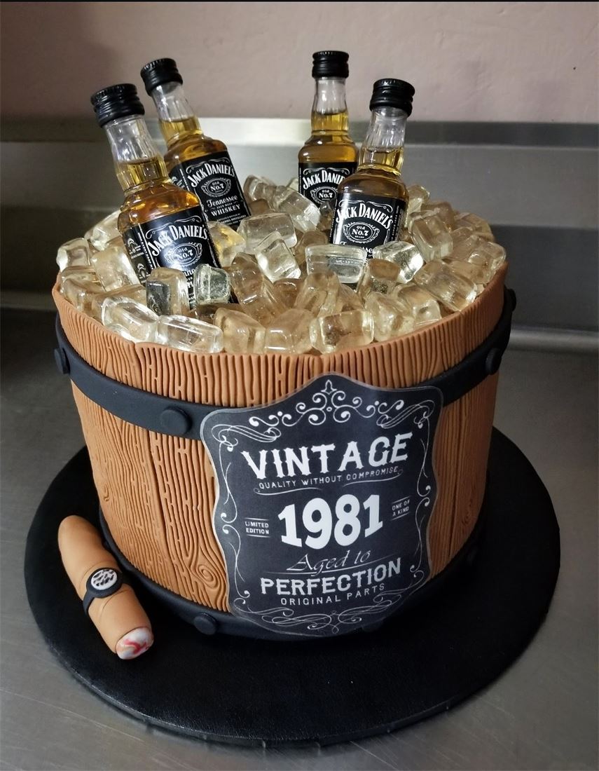 Whiskey barrel cake with edible bottles for a vintage 1981 birthday