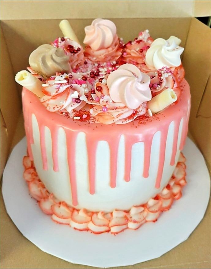 Pink and cream drip cake with candy decorations