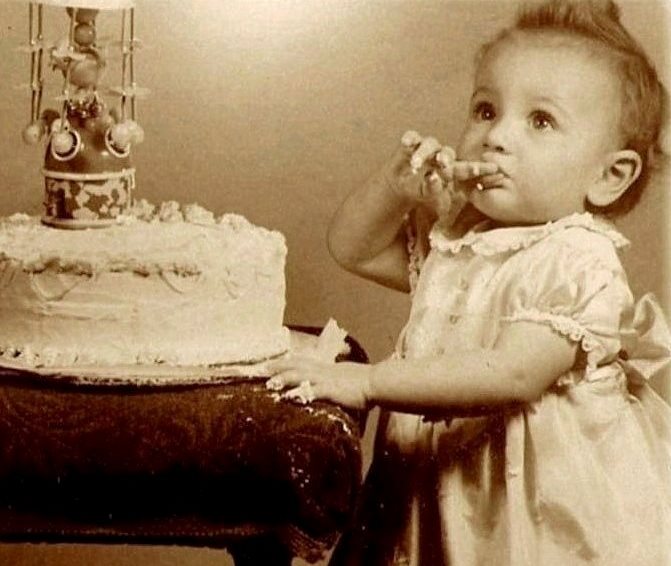 Vintage photograph of a small child tasting the icing of a birthday cake