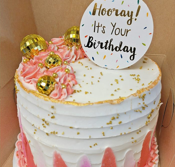 Pink and gold celebration cake with a hand-lettered birthday topper