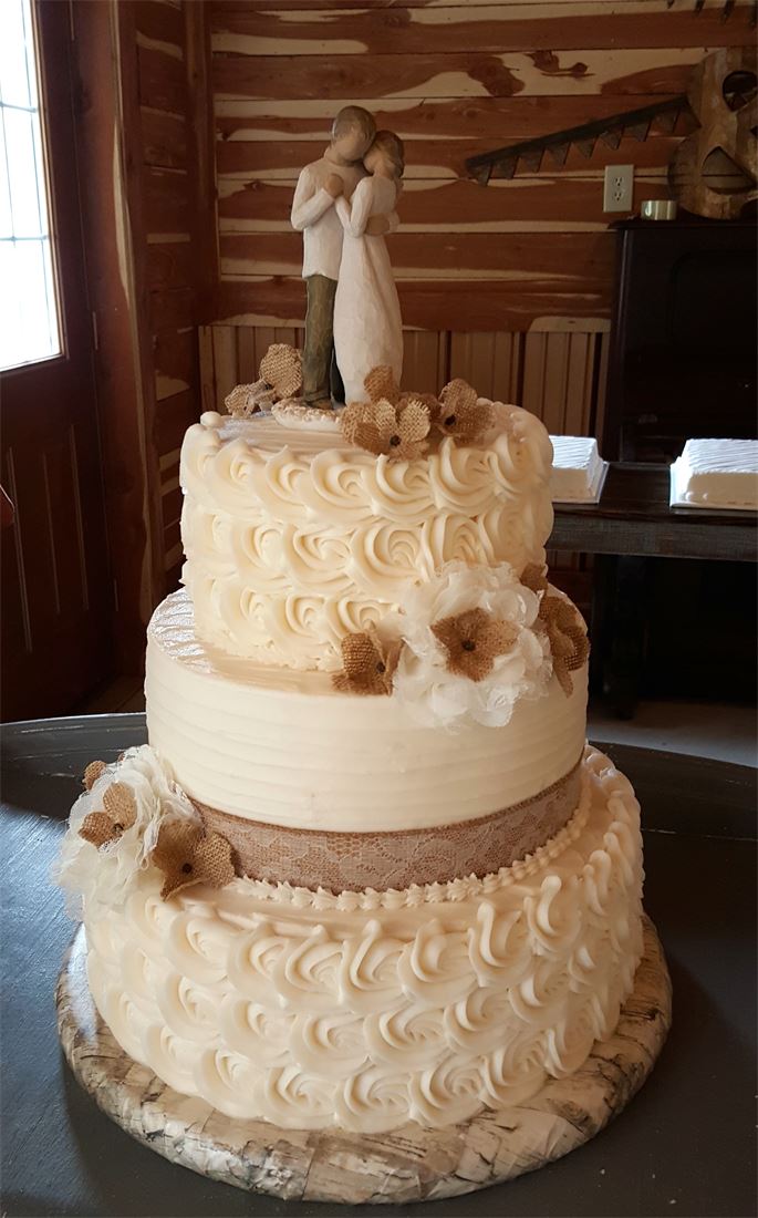 Buttercream wedding cake with burlap ribbon and a bride and groom topper