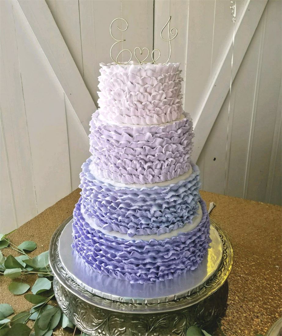 Four-tier lavender ruffled wedding cake with white blossoms