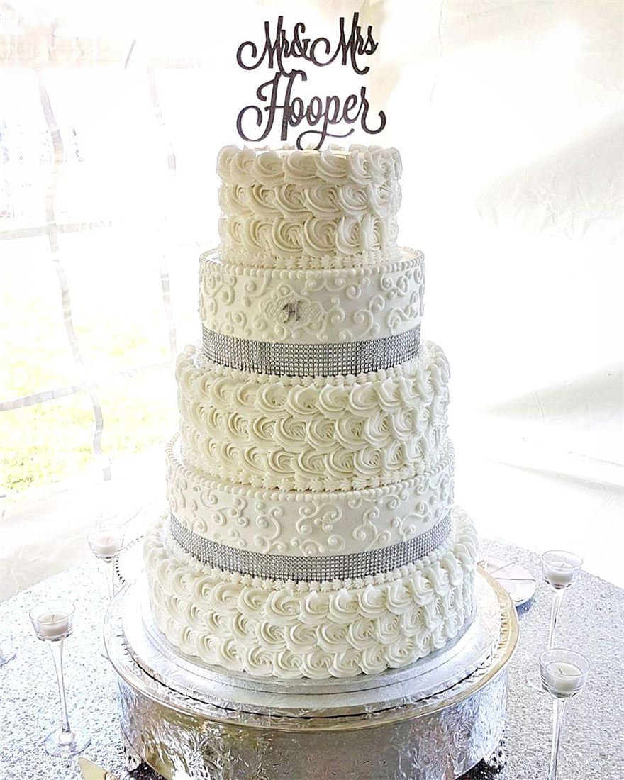Four-tier white wedding cake with lace piping and a Mr and Mrs topper