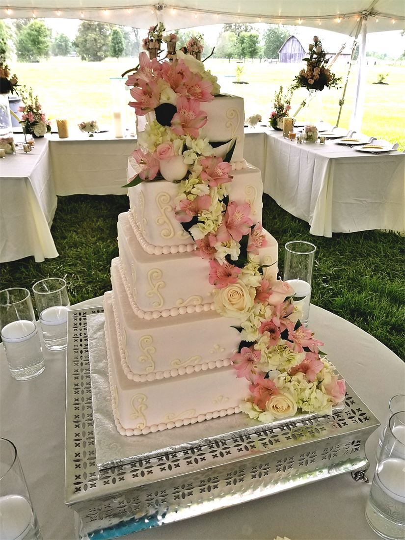 Blush tiered wedding cake with a cascade of pink flowers