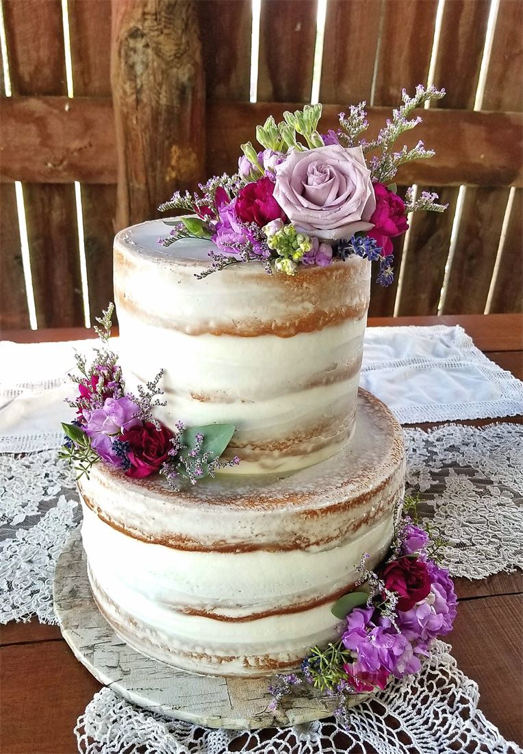 Naked wedding cake decorated with purple and pink garden flowers