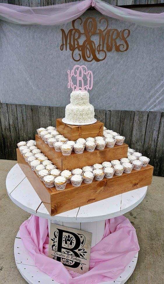 White wedding cake with a pink ribbon and monogram on a draped table