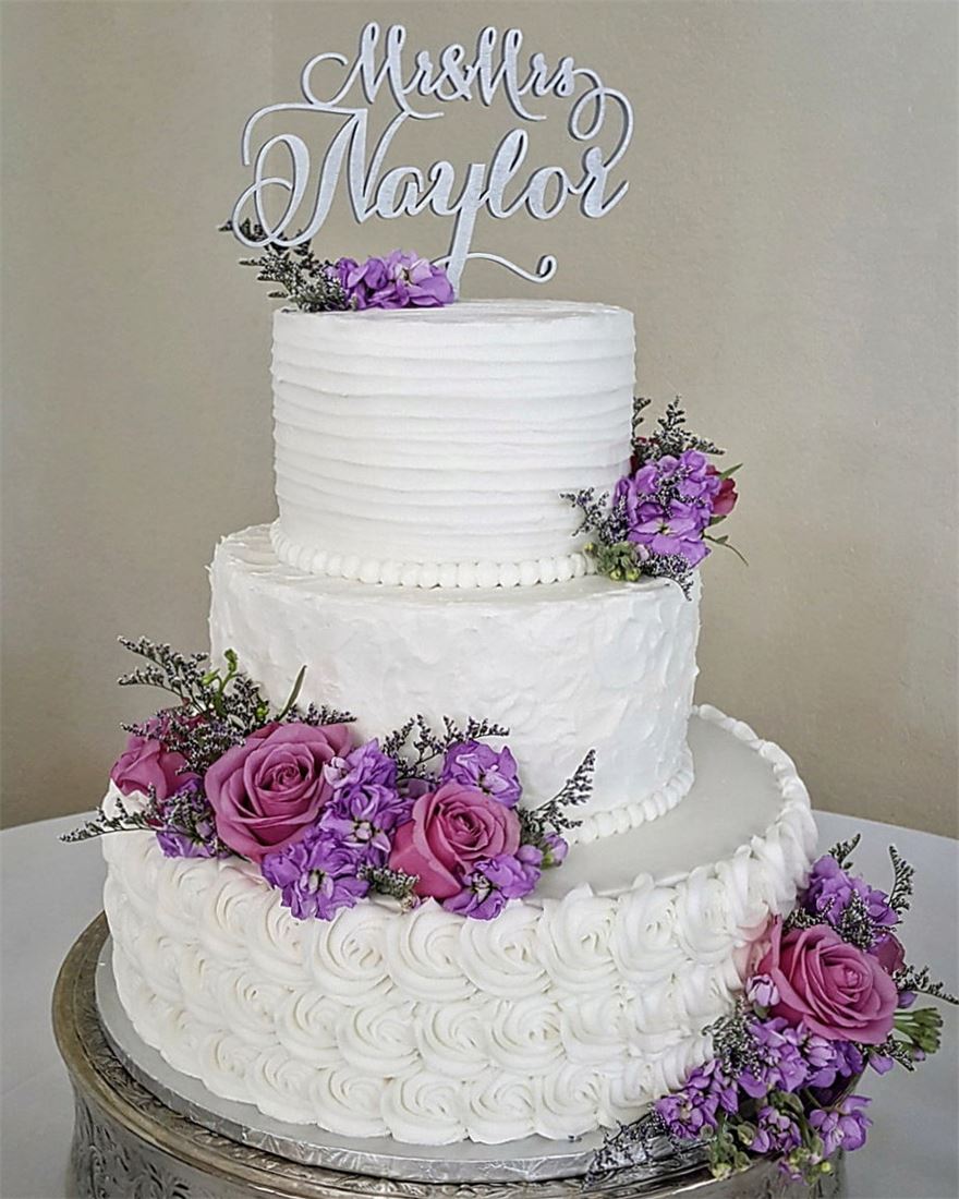 White wedding cake with purple and pink flowers and a Mr and Mrs topper