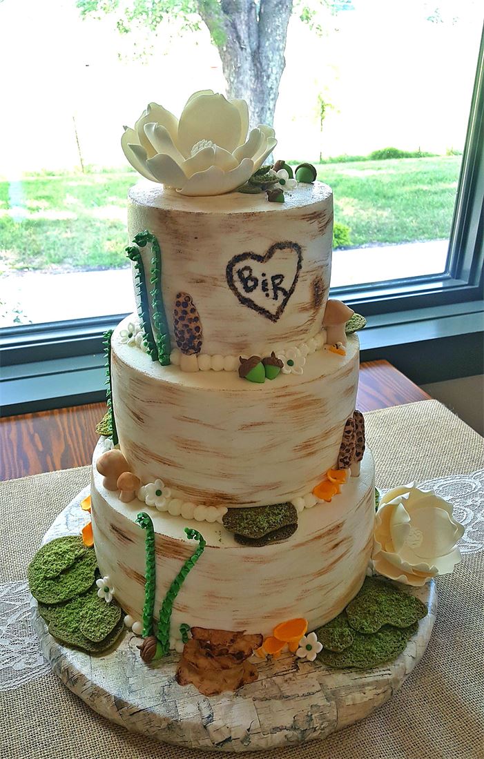 Rustic tiered cake decorated with greenery and a carved heart