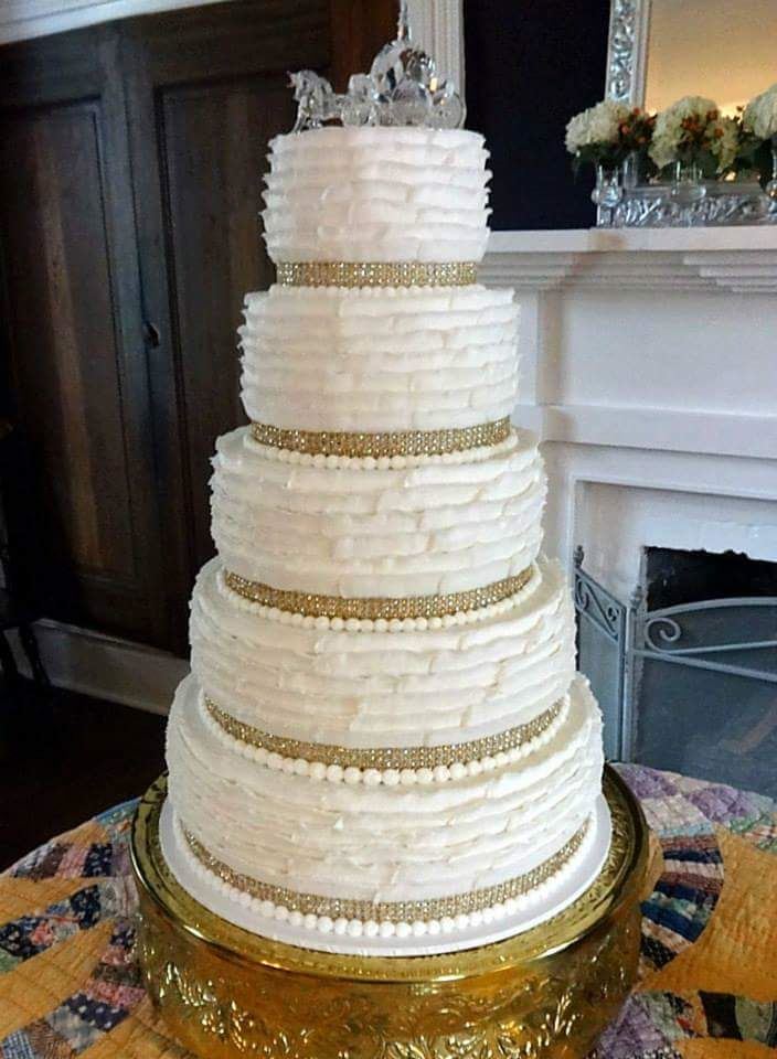 Textured white wedding cake displayed on a fireplace mantel