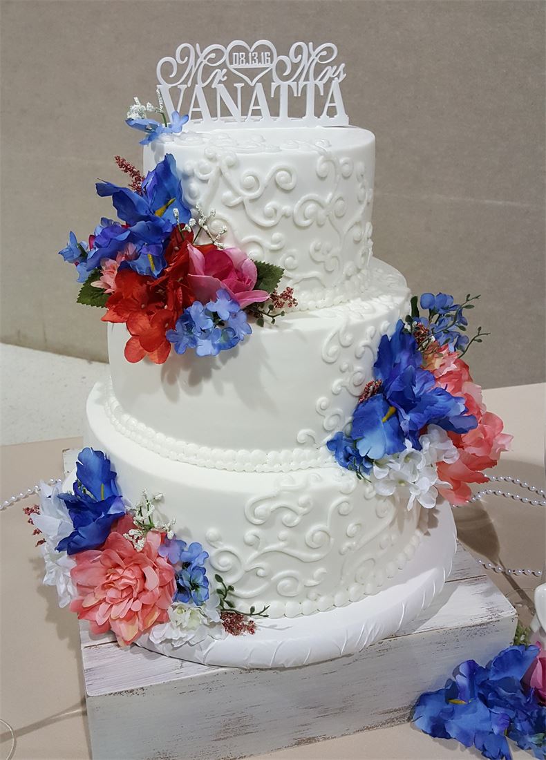 White wedding cake with piped blue and pink flowers
