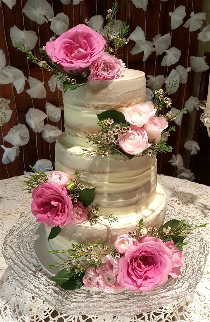 Naked cake with pink roses and warm string lights