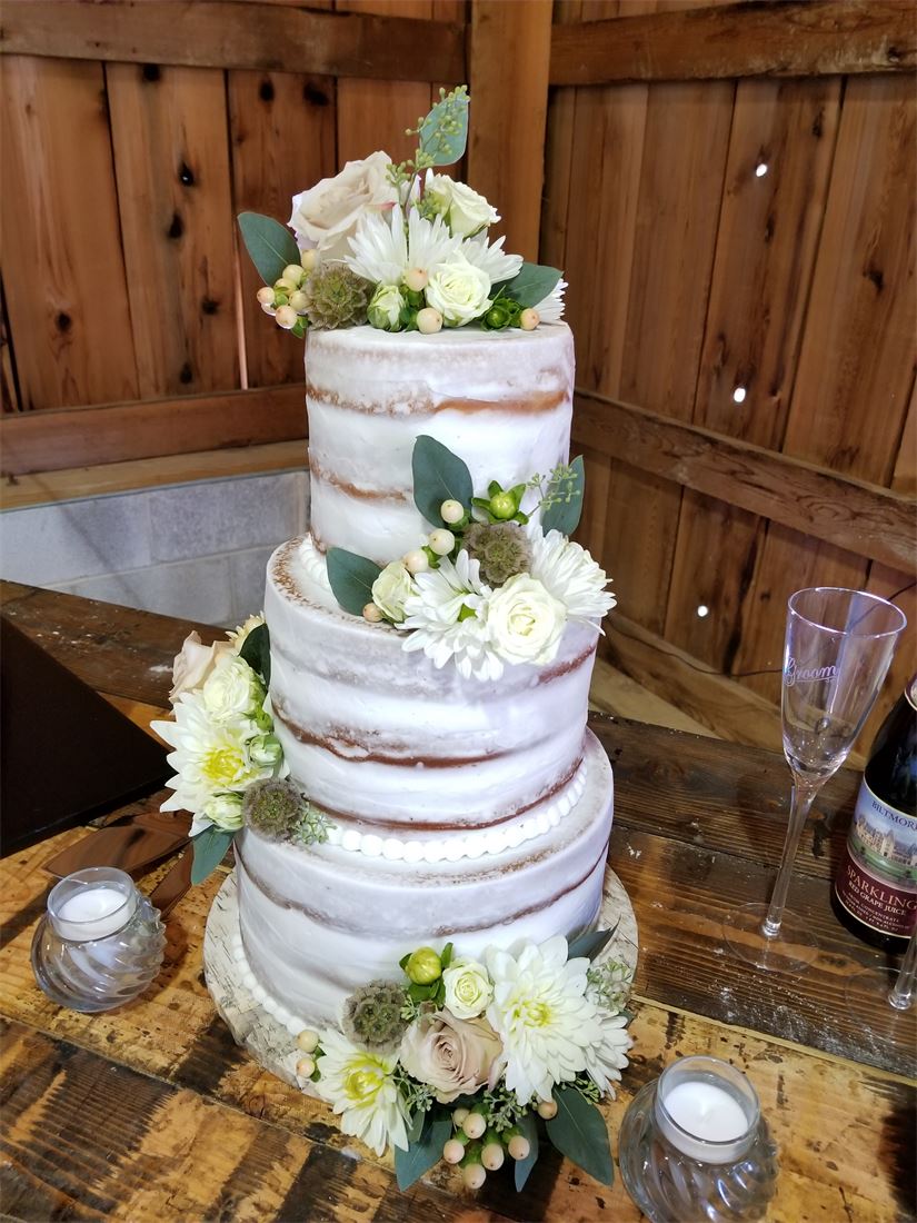 White tiered wedding cake with greenery and pale flowers