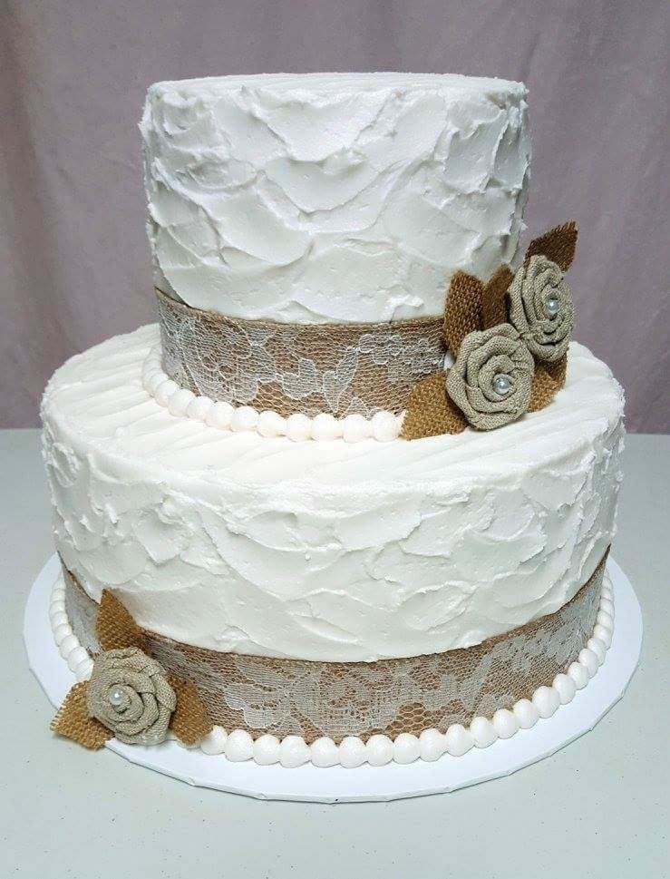 Buttercream wedding cake with burlap ribbon and greenery